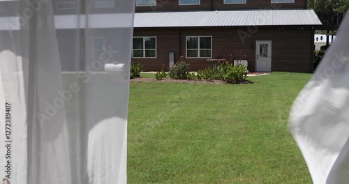 White cloth curtains on a gazebo waving in the wind at a wedding venue on a sunny day