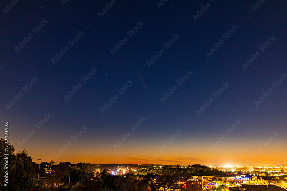 Fototapeta premium Comet flies through sunset light over city