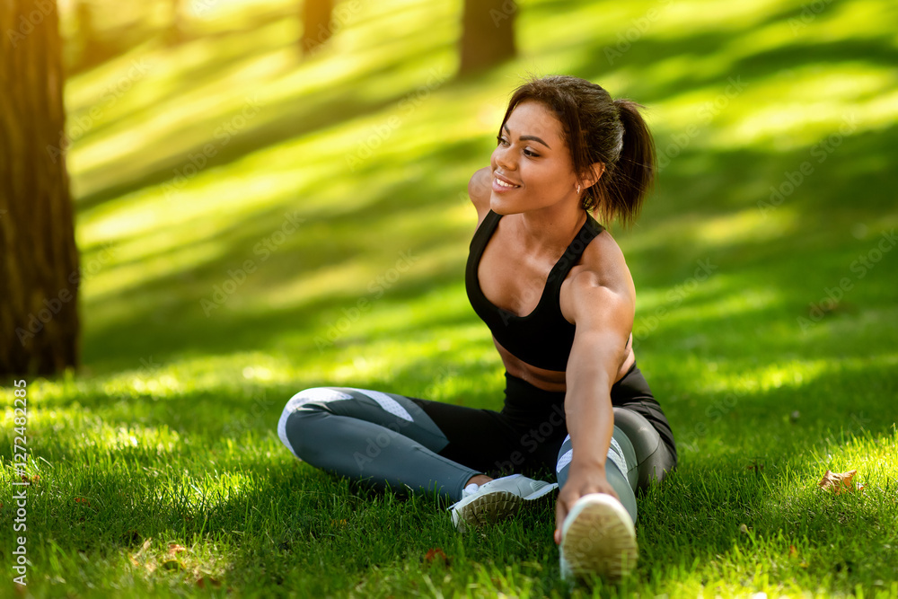 Healthy african woman warming up on the grass before jogging by park, free space Healthy african woman warming up on the grass before jogging by park, free space