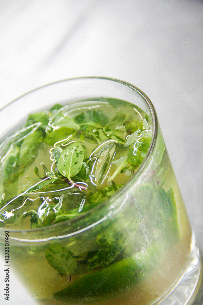 Close-up vertical shot of a refreshing Cuban Mojito with fresh mint, lime, and brown sugar, bursting with vibrant colors. Close-up vertical shot of a refreshing Cuban Mojito with fresh mint, lime, and brown sugar, bursting with vibrant colors.