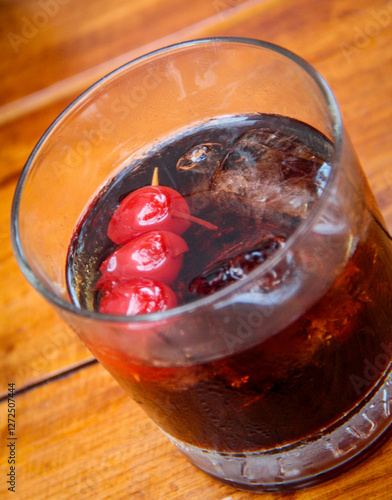 Close-up of a refreshing cherry cola served in an old-fashioned glass, garnished with maraschino cherries, ice cubes. photo