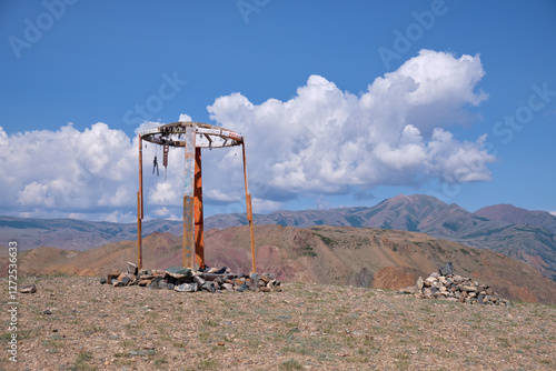 Religious wooden construction in Altai mountains. In background Kurai mountain range under blue sky and clouds. photo