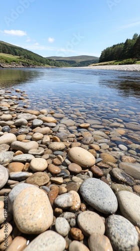 Serene river landscape with smooth stones in foreground, lush hills in background
