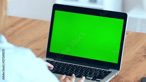 Wallpaper Mural A person is focused on their laptop, which displays a plain green screen. The setting is a cozy workspace with a wooden desk and minimal clutter, creating a productive atmosphere. Torontodigital.ca