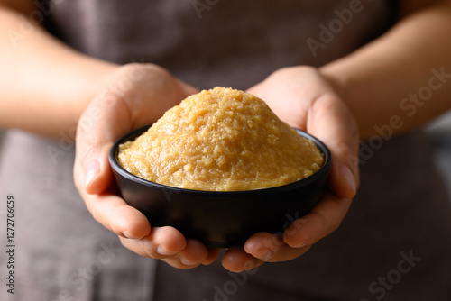 Bild auf Leinwand Miso paste in black bowl holding by hand, Japanese seasoning made from fermentin