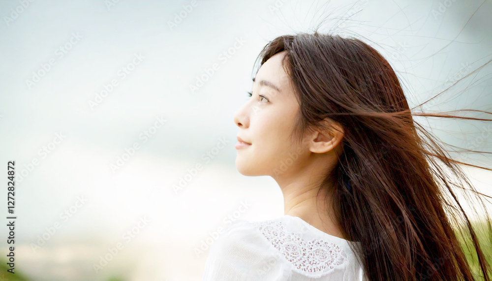 風に髪をたなびかせている髪の長い若い女性。曇り空の背景。 風に髪をたなびかせている髪の長い若い女性。曇り空の背景。