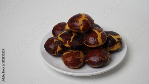 A collection of raw jengkol placed on a white plate with a white base and background (isolated white).