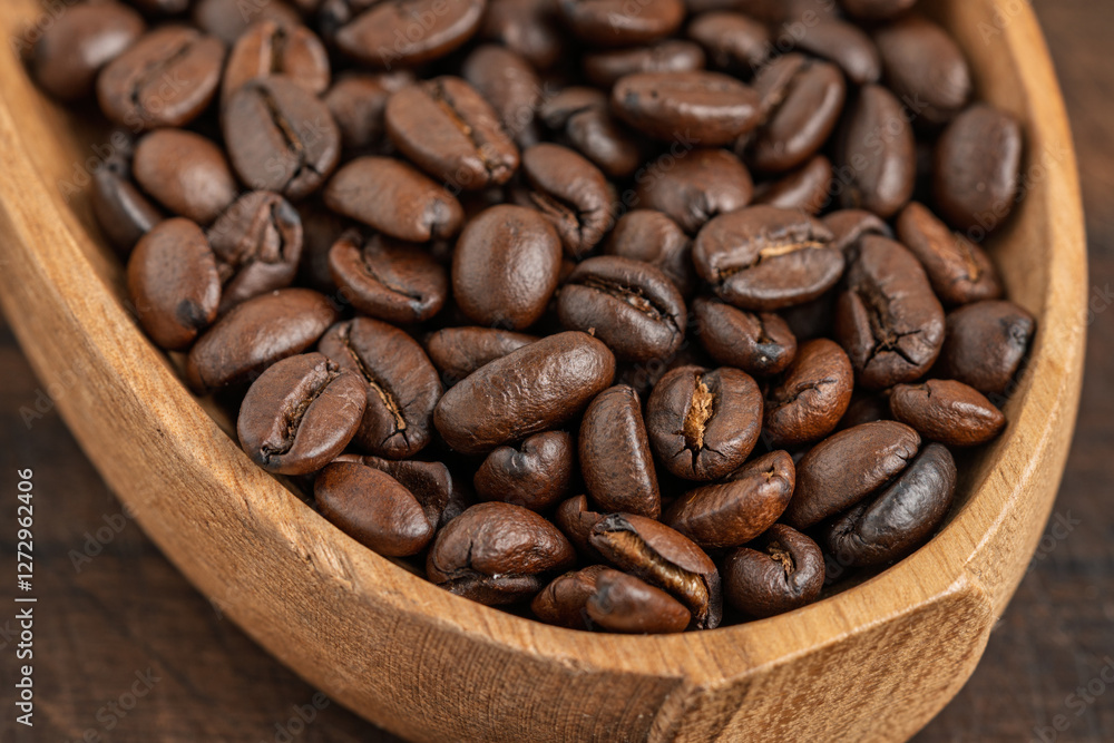 Fototapeta premium Close-up of roasted coffee beans in a wooden bowl. Rich aroma and texture of freshly roasted coffee.
