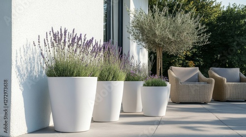 Three modern white plant pots on the terrace, next to them is an outdoor floor lamp, and in one of these flowerpots, there is lavender and other plants