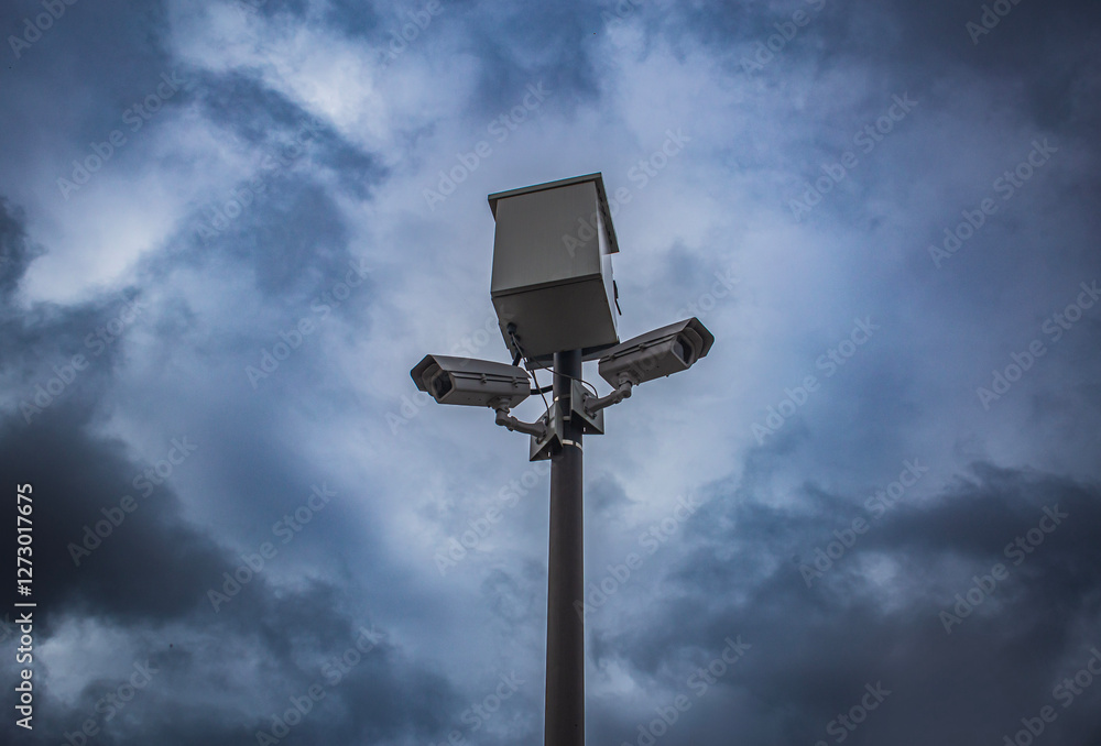 surveillance camera fining people and keeping control, against the background of severe thunderclouds with a thunderstorm. the problem of freedom and personal life in the 21st century surveillance camera fining people and keeping control, against the background of severe thunderclouds with a thunderstorm. the problem of freedom and personal life in the 21st century