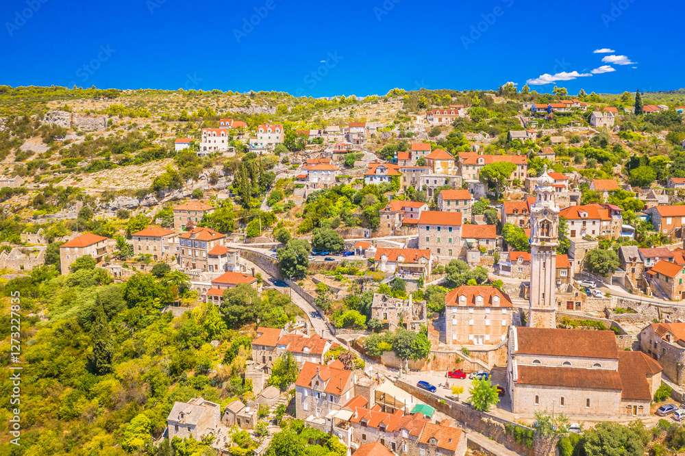 Fototapeta premium A breathtaking aerial view of Lozisca on Brac Island, Croatia, showcasing its iconic bell tower, and the surrounding Mediterranean countryside, capturing the beauty of this charming island village