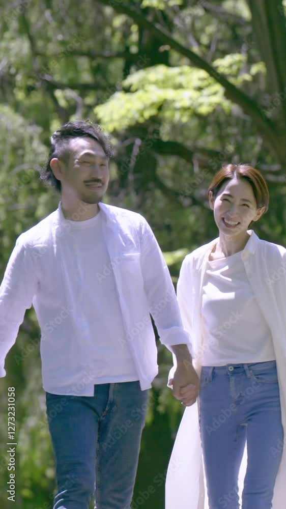 新緑の中夫婦で仲良く手をつないで歩く 見つめ合う縦動画 新緑の中夫婦で仲良く手をつないで歩く 見つめ合う縦動画