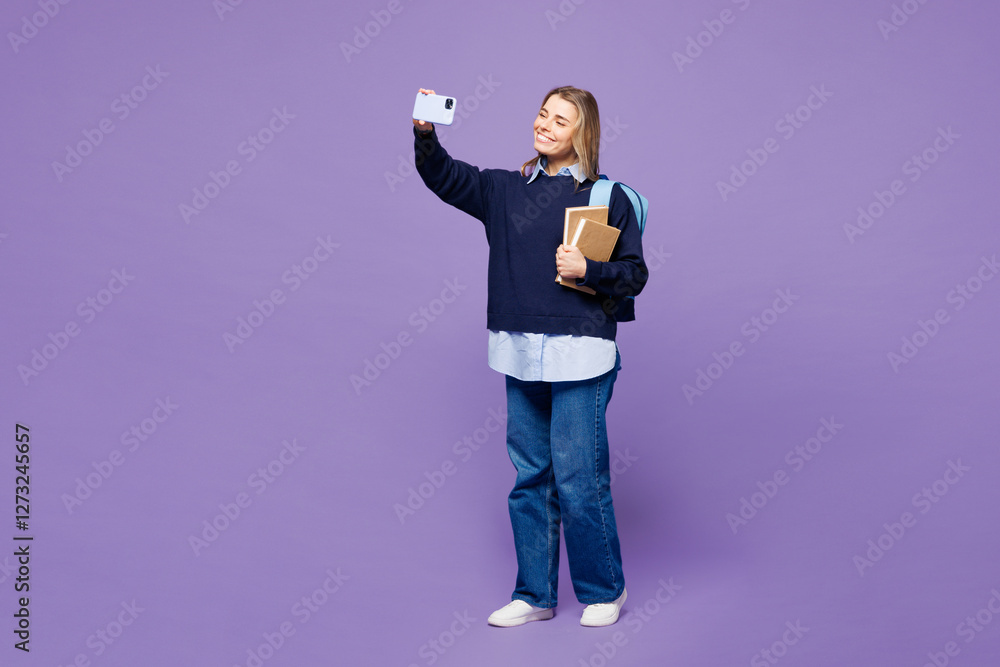 Full body young girl student wear blue casual clothes glasses backpack bag hold books doing selfie shot on mobile cell phone isolated on plain purple background High school university college concept Full body young girl student wear blue casual clothes glasses backpack bag hold books doing selfie shot on mobile cell phone isolated on plain purple background High school university college concept