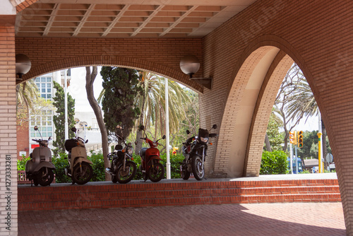 Motorcycles lined up under brick arches. Urban details, transportation, and architectural elements. photo