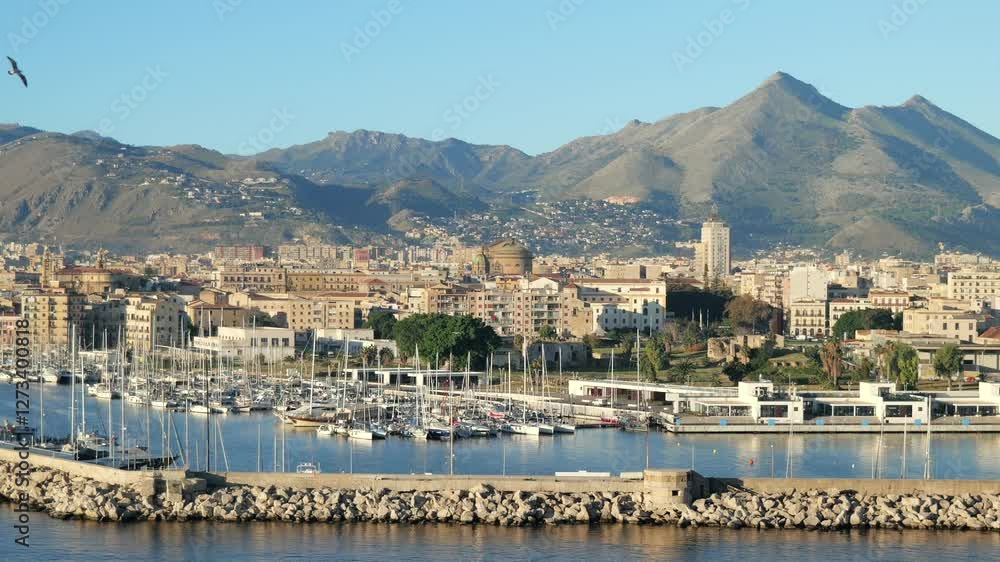 The marina of Palermo, Sicily, with sailboats docked along the harbor. Monte Pellegrino and the city skyline form a stunning backdrop in the golden morning light, highlighting the Mediterranean. The marina of Palermo, Sicily, with sailboats docked along the harbor. Monte Pellegrino and the city skyline form a stunning backdrop in the golden morning light, highlighting the Mediterranean.