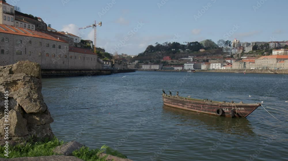 Old wooden boat in Duoro river with cityscape of Porto in background, seagull flying around Old wooden boat in Duoro river with cityscape of Porto in background, seagull flying around