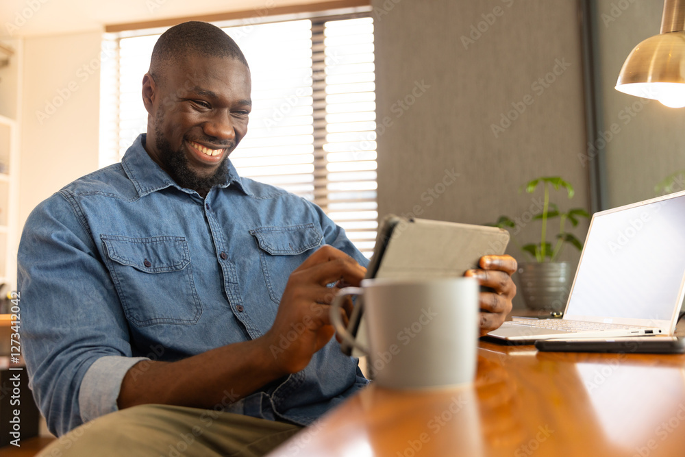 African American man smiling while using tablet at home African American man smiling while using tablet at home