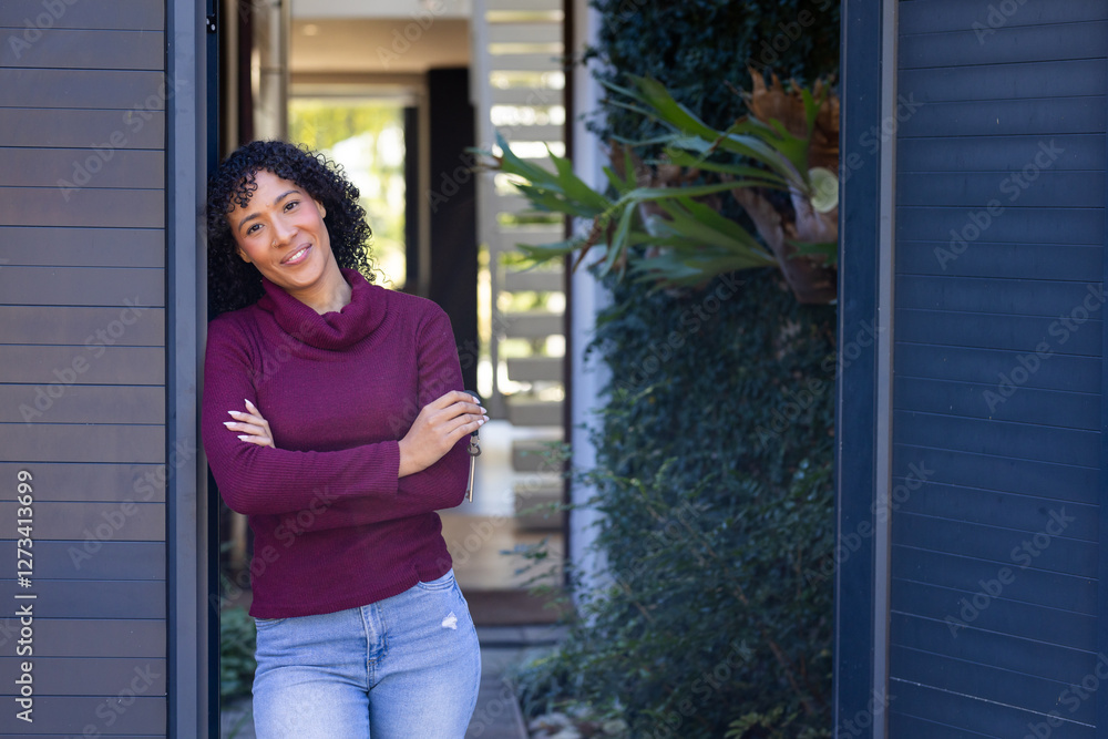 Woman in maroon sweater standing in doorway, crossing arms and smiling, copy space Woman in maroon sweater standing in doorway, crossing arms and smiling, copy space