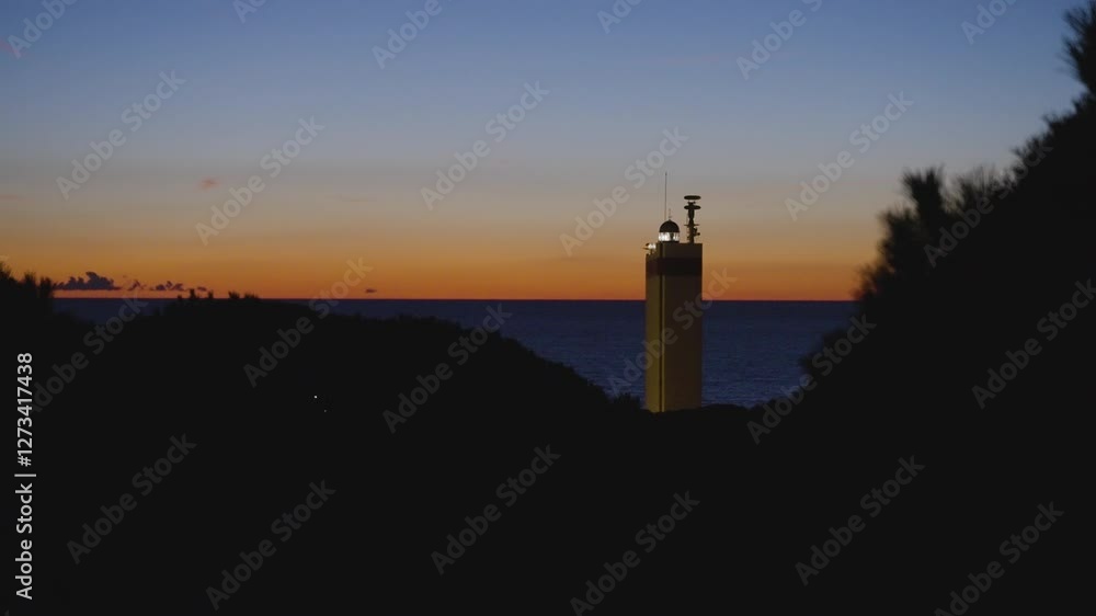 Glowing lighthouse and sunset sky, static view Glowing lighthouse and sunset sky, static view