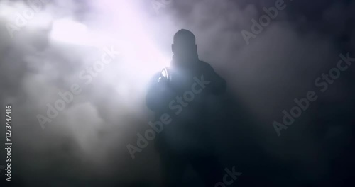 Black silhouette of man with flashlight shining in thick grey smoke
