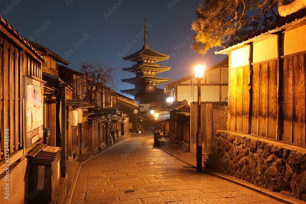 Fototapeta premium Beautiful night view of Yasaka Pagoda (Hōkanji Temple) in Kyoto, Japan, with warm street lights illuminating the traditional wooden houses along the historic alley