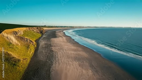 Wallpaper Mural A serene beach view with gentle waves and cliffs under a clear blue sky. Torontodigital.ca