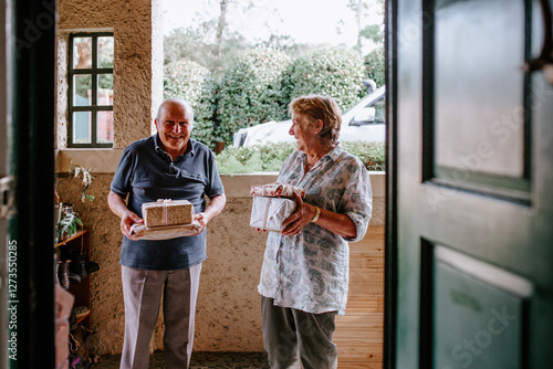 Senior couple bringing gifts greeted at the doorway photo