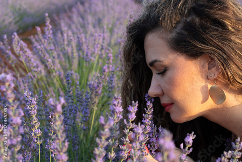 Curly-haired woman enjoying the scent of lavender in a field