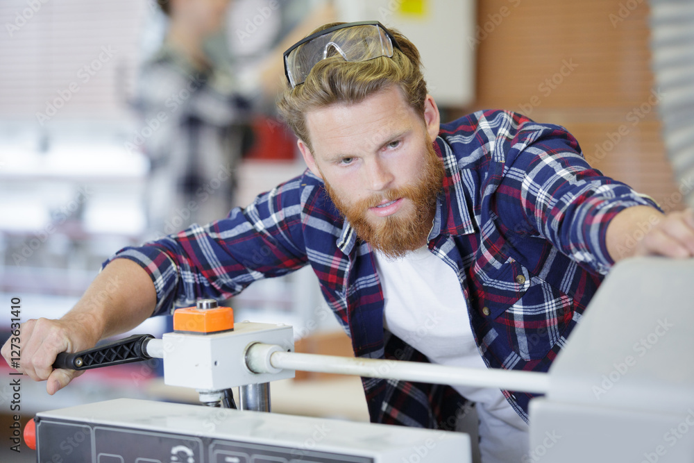 young worker in factory using machine