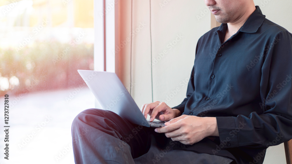 flexible work, digital remote job opportunities, a man working on a laptop while sitting near a window with natural lighting. The relaxed and bright atmosphere emphasize, mobility, and online business
