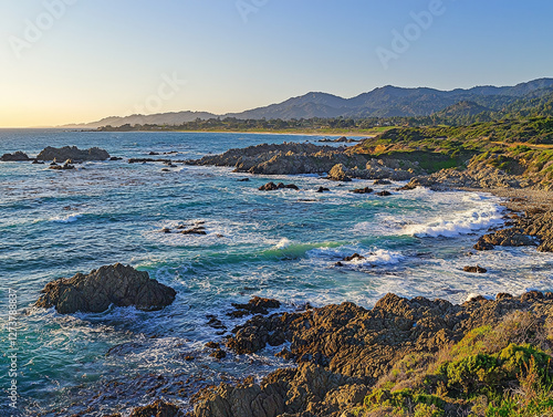 Coastal sunset view; ocean waves crashing against rocky shoreline photo