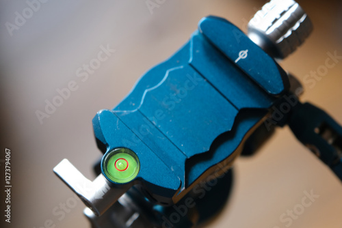 A close-up of a blue and silver tripod head with a bubble level, used for precise camera positioning. Intricate details and precision engineering. photo