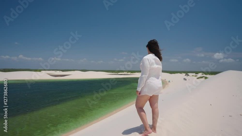 Panorama landscape of woman on desert dunes between rain water lagoons. Brazil Northeast.
