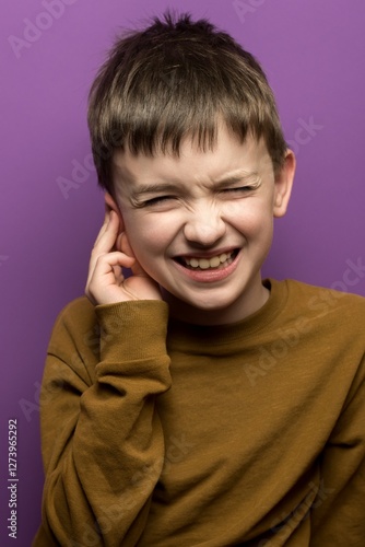 Wallpaper Mural Child holding ear, wincing in pain, purple background. Ideal for themes of earache, childhood health issues, and expressions of discomfort. Torontodigital.ca