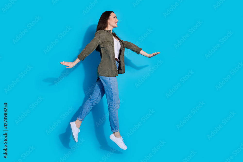 Obraz premium Young woman in casual outfit jumping happily on a bright blue background
