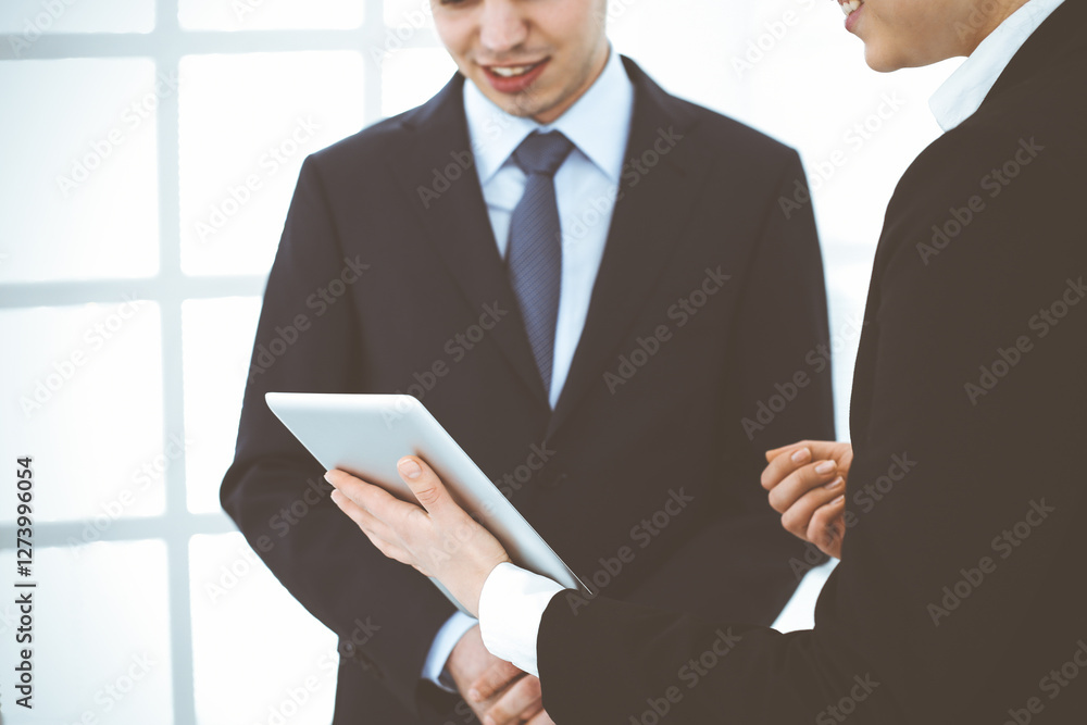 Businessman and woman using tablet computer for discussing questions in office. Partners or colleagues at meeting. Business cooperation concept Businessman and woman using tablet computer for discussing questions in office. Partners or colleagues at meeting. Business cooperation concept