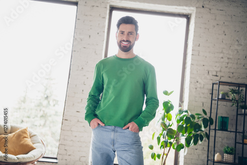 Young man stands smiling in a brightly lit modern living room with indoor plants photo