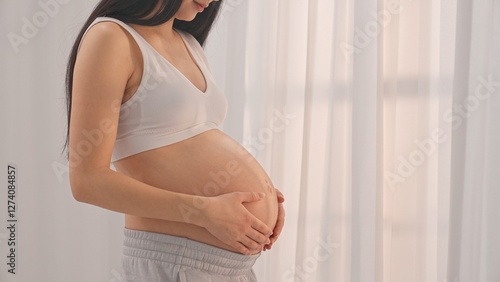 Young happy Asian pregnant woman posing in studio with white curtains in background Free Download Young happy Asian pregnant woman posing in studio with white curtains in background - GFXLoad