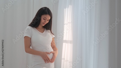 Free Download Young happy Asian pregnant woman posing in studio with white curtains in background - GFXLoad