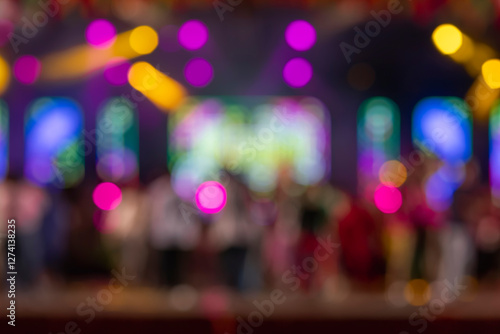Blurred concert stage with colorful neon lights and vibrant audience