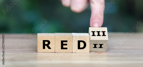 Hand turns cube and changes the expression 'RED II' to 'RED III'. Symbol for the new European Renewable Energy Directive III.