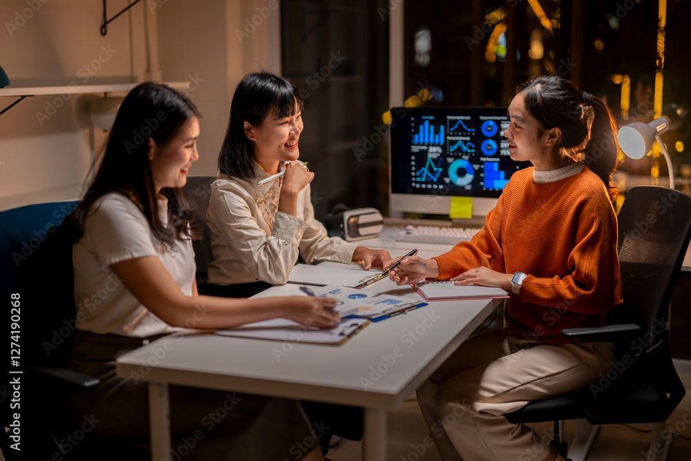 Three women are sitting at a table with a computer monitor in front of them Three women are sitting at a table with a computer monitor in front of them