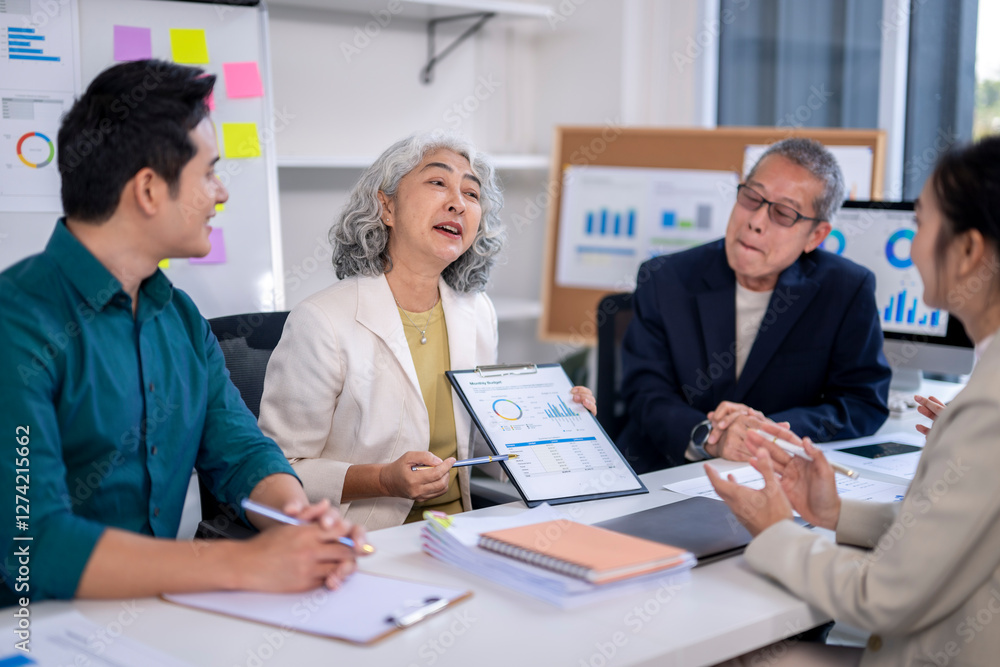 A group of people are sitting around a table with a woman holding a presentation A group of people are sitting around a table with a woman holding a presentation
