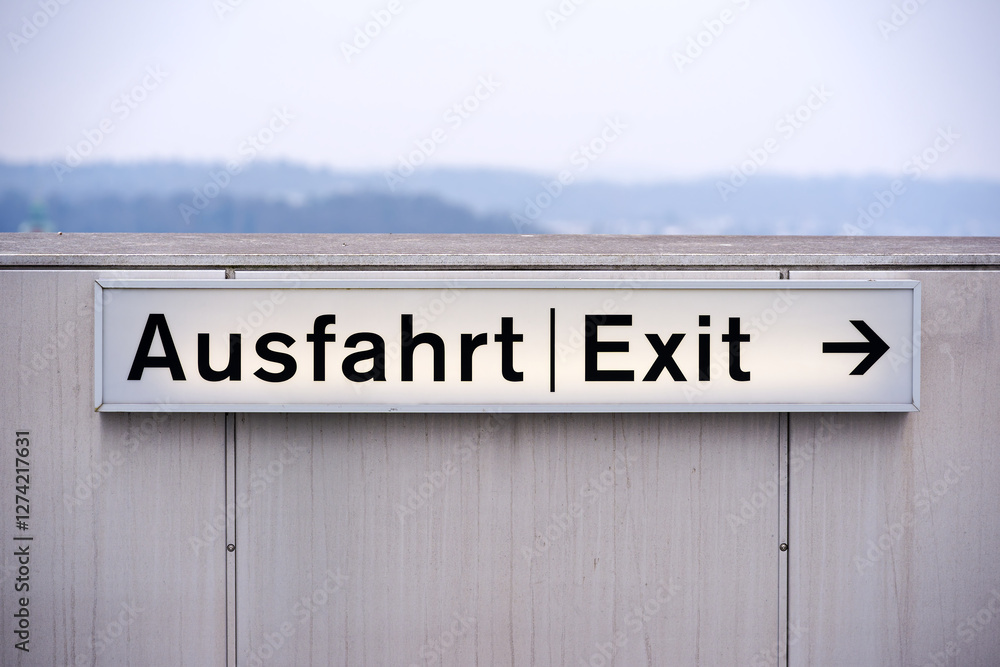 Illuminated exit direction sign at rooftop of parking deck at Swiss Airport Zürich Kloten on a gray winter day. Photo taken February 17th, 2025, Zurich Kloten, Switzerland. Illuminated exit direction sign at rooftop of parking deck at Swiss Airport Zürich Kloten on a gray winter day. Photo taken February 17th, 2025, Zurich Kloten, Switzerland.