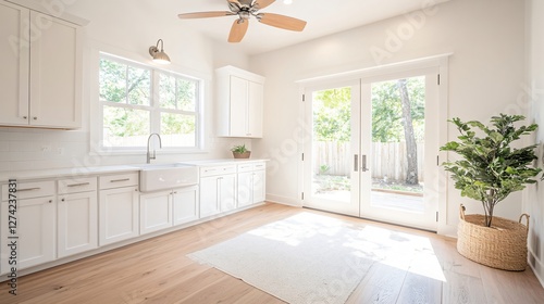 Modern bright white kitchen interior with wooden floor, ceiling fan and glass doors leading to backyard. Empty clean minimalist home design with natural light and copy space photo