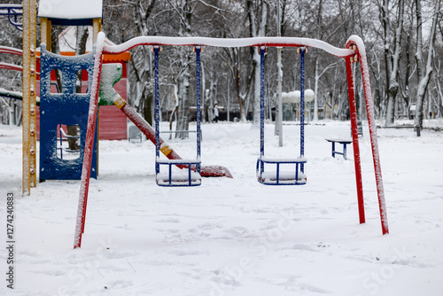 Children's swings in the park on the playground in winter