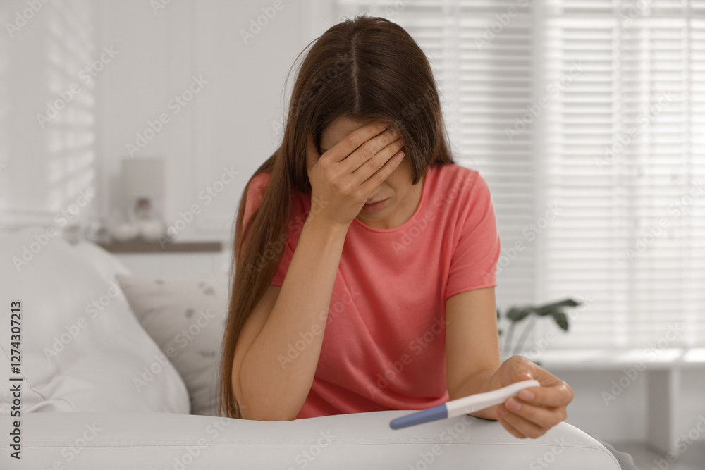Upset woman with negative pregnancy test on sofa at home Upset woman with negative pregnancy test on sofa at home