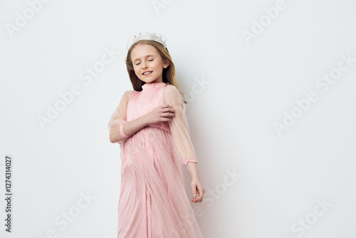 Young girl in a pink dress with a crown, expressing joy and innocence, perfect for children s fashion, celebrations, and seasonal themes of spring or summer photo