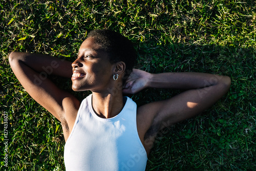 Wallpaper Mural Young black woman relaxing lying on green grass smiling with hands behind head Torontodigital.ca