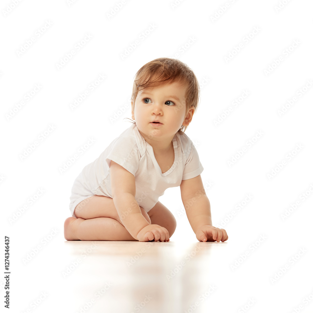 Little, charming baby, dressed white onesie, kneeling and gazing sideways with curious expression against white background. Concept of childhood, wonder, learning, born and growth. Little, charming baby, dressed white onesie, kneeling and gazing sideways with curious expression against white background. Concept of childhood, wonder, learning, born and growth.